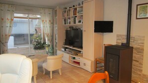 A living room with a television, a bookshelf, a fireplace, and a dining area with chairs. - Charming new house in downtown Les Sables D¥Olonne  (Les Sables d'Olonne)