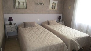 A room with two beds, a nightstand with a lamp, and a wall-mounted light fixture. - Charming new house in downtown Les Sables D¥Olonne  (Les Sables d'Olonne)