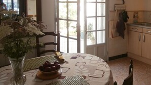 A kitchen with a dining table, a vase with flowers, and a window with a view of the outside. - Nice spacious village house and sunny downtown (Saint-Rémy-De-Provence)