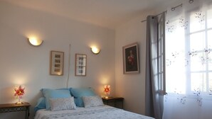 A bedroom with a bed, two bedside tables, a wall-mounted light, and a window with curtains. - Nice spacious village house and sunny downtown (Saint-Rémy-De-Provence)