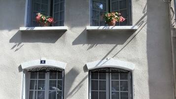 A building with three windows, each with a small balcony and potted plants.