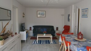 A modern living room with a sofa, coffee table, and dining area with chairs and a table. - Cabourg - Comfortable apartment 1 / 6pers WIFI in RDJ with terrace 100m beach (Cabourg)