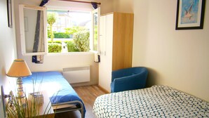 A bedroom with a bed, a chair, a window, and a radiator. - Cabourg - Comfortable apartment 1 / 6pers WIFI in RDJ with terrace 100m beach (Cabourg)