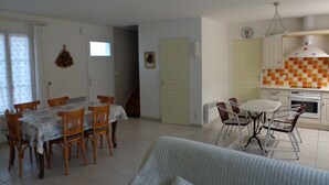 A dining area with a table and chairs, a kitchen with a checkered backsplash, and a living area with a sofa. - Pretty house classified 3 *** style retais (Saint-Martin-De-Ré)