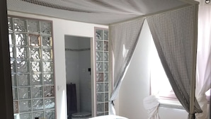 Un dormitorio con cama, ventana con cortina a cuadros y vista al exterior.