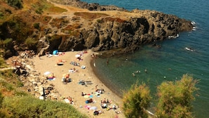 Una playa costera con terreno rocoso y aguas azules cristalinas.
