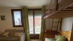 A compact room with a bunk bed, a sofa, and a window with curtains. - COQUET STUDIO FEET OF THE TRACKS WELL EQUIPPED EXCEPTIONAL !!! ! (Risoul)