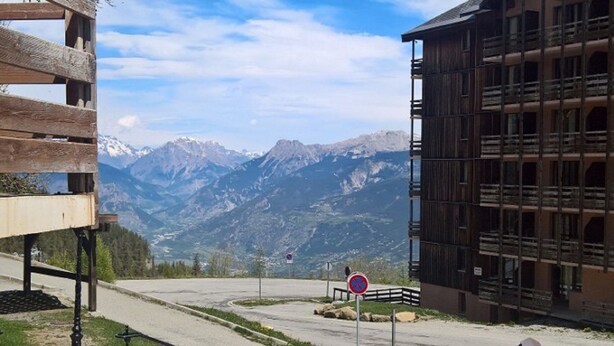 A building with a mountain view, a no parking sign, and a wooden structure in the foreground. - COQUET STUDIO FEET OF THE TRACKS WELL EQUIPPED EXCEPTIONAL !!! ! (Risoul)