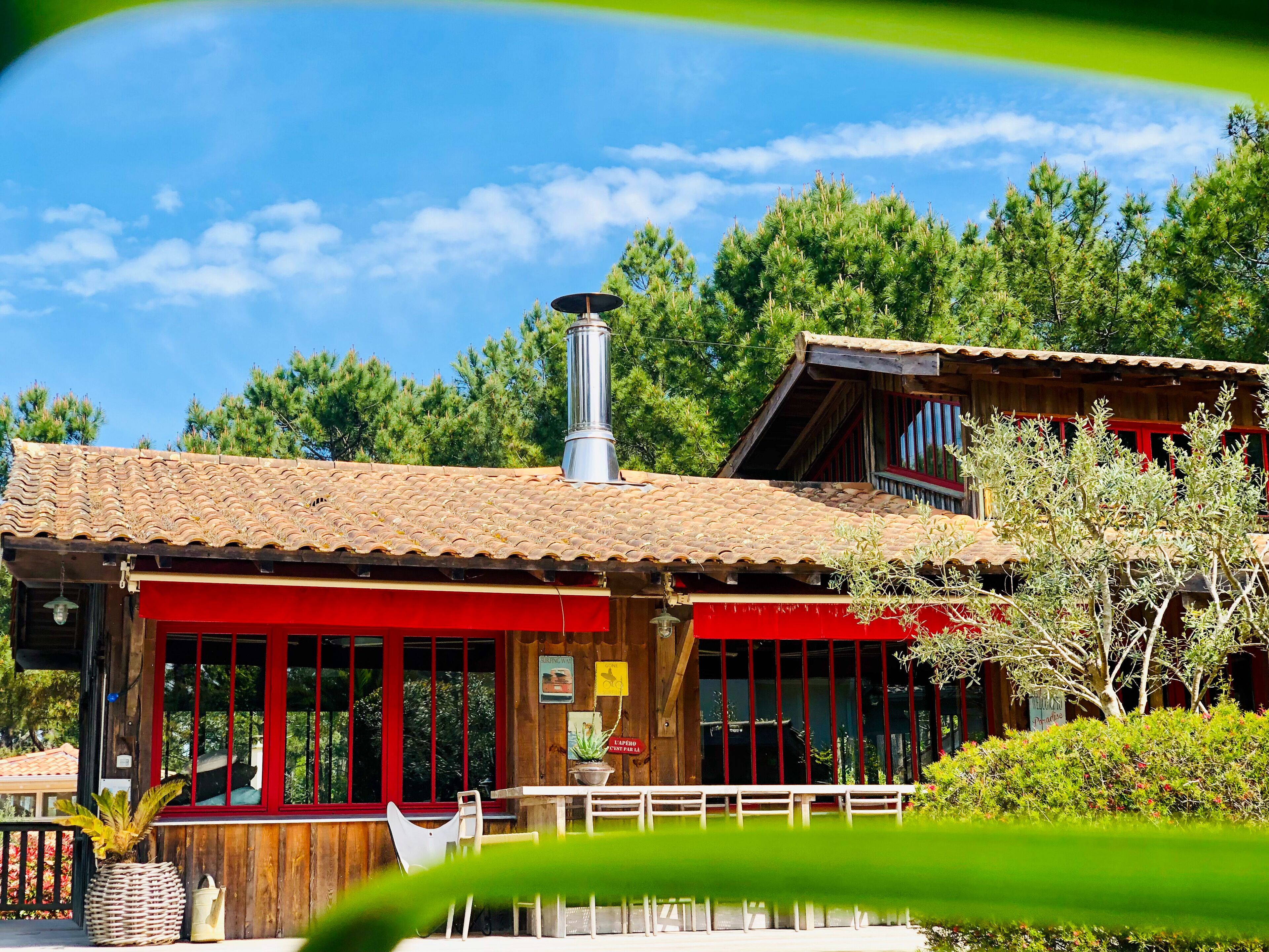 A wooden building with a tiled roof, a chimney, and a red awning.