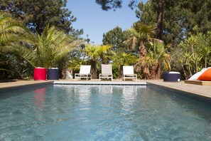 A swimming pool with white lounge chairs and a wooden deck. - Large charming cabin (Lège-Cap-Ferret)