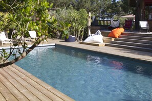 A wooden deck with a pool, lounge chairs, and a wooden staircase leading to a covered area. - Large charming cabin (Lège-Cap-Ferret)