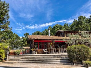 A two-story wooden building with a red facade, a chimney, and a staircase leading to the entrance. - Large charming cabin (Lège-Cap-Ferret)