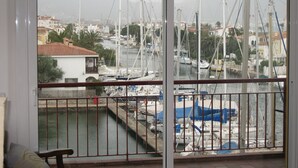 Un balcon avec vue sur une marina, où l’on aperçoit des bateaux et des bâtiments en arrière-plan.
