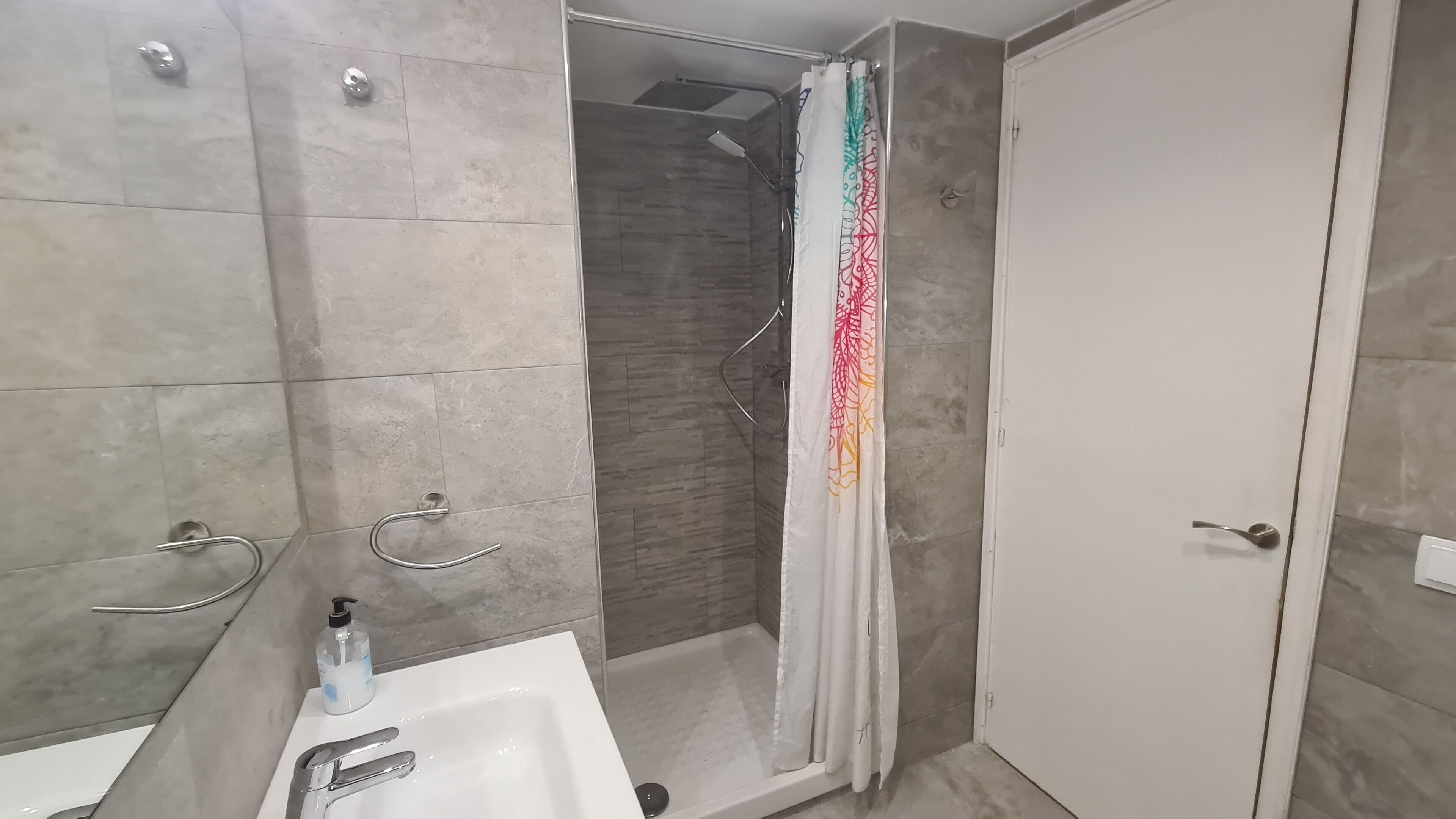 Un baño moderno con ducha, lavamanos e inodoro.