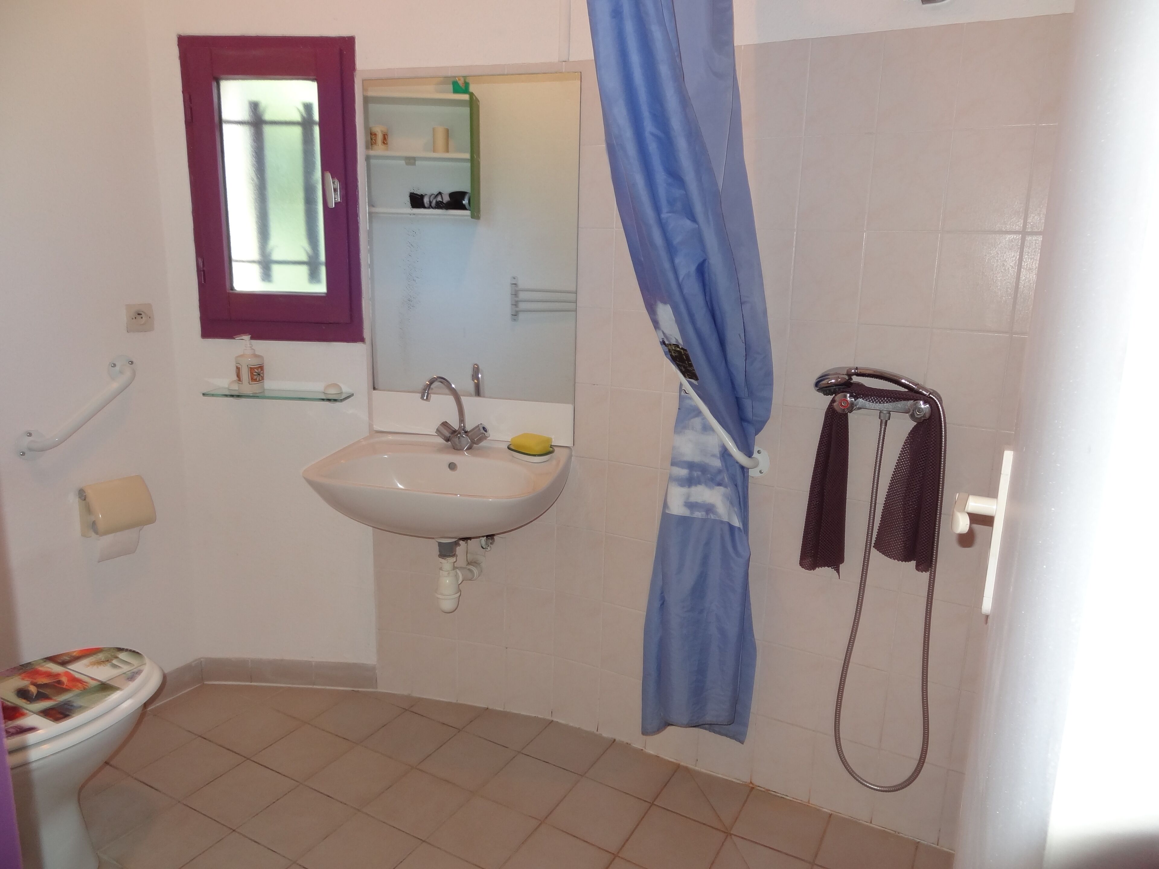 Et badeværelse med håndvask, spejl, brusebad og toilet.