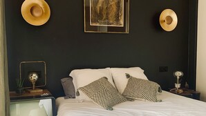 A bedroom with a bed, two nightstands, a wall-mounted picture, and two wall-mounted hats. - The Zen villa, sun and idleness (Pinet)