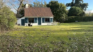 Une petite maison avec un toit en tuiles, un jardin parsemé de feuilles et un banc.