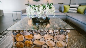A glass-top coffee table with a stone base, a vase with white flowers, and a patterned rug. - Architect-designed villa between town center and beach - Heated pool (Capbreton)