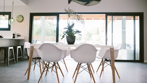 A modern dining area with a white table and chairs, a potted plant, and a large fish decoration on the wall. - Architect-designed villa between town center and beach - Heated pool (Capbreton)