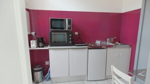 A compact kitchen with white cabinets, a microwave, a toaster, and a sink.