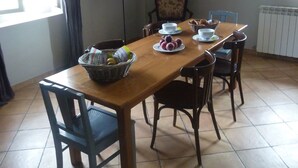 A dining area with a wooden table, four chairs, a fruit bowl, and a white decorative piece on the wall. - Provencal house in a quiet and in the heart of the village of Gigondas (Gigondas)