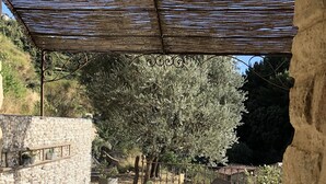 An outdoor patio with a wooden table and chairs, surrounded by potted plants and a stone wall. - Provencal house in a quiet and in the heart of the village of Gigondas (Gigondas)