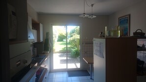 A kitchen with a view to a garden, a refrigerator, and a sink. - Between Saint-malo and Cancale, ideal for families or friends, 2 kms from the beach (Saint-Coulomb)