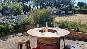 An outdoor dining area with a round table, four wine glasses, and two stools. - Between Saint-malo and Cancale, ideal for families or friends, 2 kms from the beach (Saint-Coulomb)