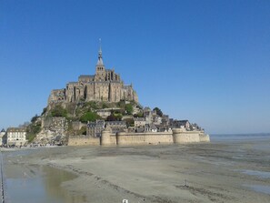 Un château historique, doté d’une tour imposante, situé sur une falaise côtière surplombant une plage.