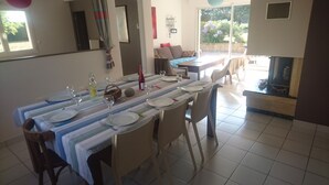 A dining area with a table set for four, including plates, glasses, and cutlery. There are chairs around the table, and a sofa is visible in the background. - Between Saint-malo and Cancale, ideal for families or friends, 2 kms from the beach (Saint-Coulomb)