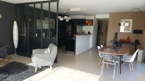 Ein moderner Wohnbereich mit Essbereich, Küche und einer Schiebeglasdoor, die zu einem Balkon führt.