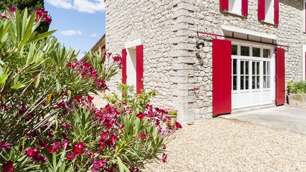 Un edificio in pietra con un basculante e persiane rosse.