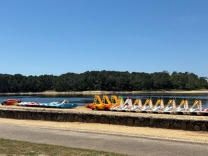 Blick auf einen See mit einer Reihe von Tretbooten und einer Steinmauer.