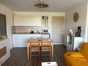 Eine moderne Küche mit weißen Schränken, einem Essbereich mit Holzkästen und einem gelben Sofa.