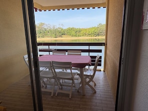 Ein Balkon mit Tisch und Stühlen mit Blick auf Wasser und Grünflächen.