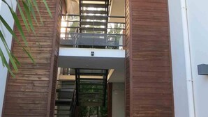 A modern building with a wooden facade, a balcony, and a staircase leading to an upper level. - Bright apartment 80 meters from the lagoon, with large covered terrace (La Saline-Les-Bains)