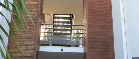 A modern building with a wooden facade, a balcony, and a staircase leading to an upper level.