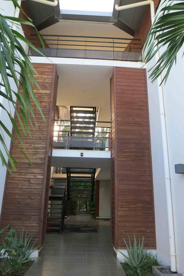 A modern building with a wooden facade, a balcony, and a staircase leading to an upper level.