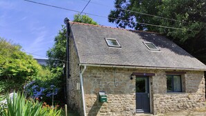 A stone house with a sloped roof, a small porch, and a door marked with the number 2. - Charming cottage in the countryside - Quaint cottage in the countryside (Langoëlan)