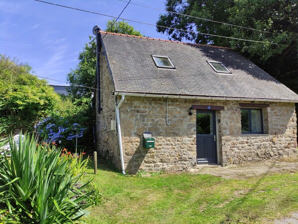 A stone house with a sloped roof, a small porch, and a door marked with the number 2. - Charming cottage in the countryside - Quaint cottage in the countryside (Langoëlan)