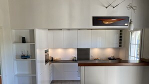 A modern kitchen with white cabinetry, a central island, and a hanging light fixture.