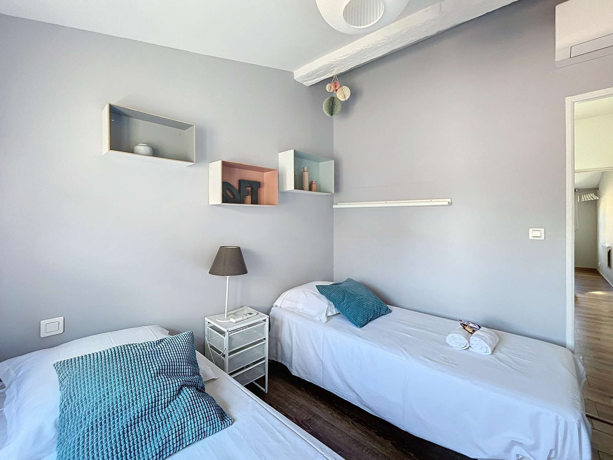 A bedroom with two beds, a bedside table, a lamp, and a mirror.