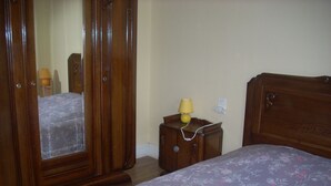 A bedroom with a wooden bed, a nightstand with a lamp, and a wardrobe. - 2-star detached holiday home (Rochesson)
