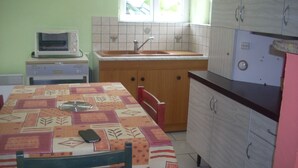 A compact kitchen with a dining table, chairs, a microwave, a sink, and cabinets. - 2-star detached holiday home (Rochesson)