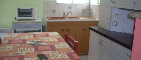 A compact kitchen with a dining table, chairs, a microwave, a sink, and cabinets.