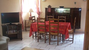 A dining area with a table set for four, a television, and a cabinet with glass doors. - 2-star detached holiday home (Rochesson)