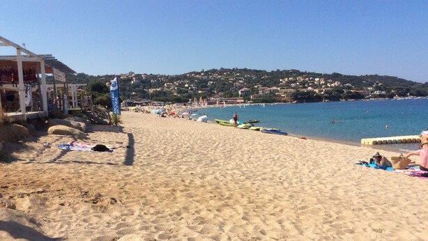 Une plage de sable offrant une vue dégagée sur la mer et une colline lointaine.