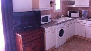 Une cuisine compacte équipée d’un lave-linge, d’un four à micro-ondes et d’un four encastré.