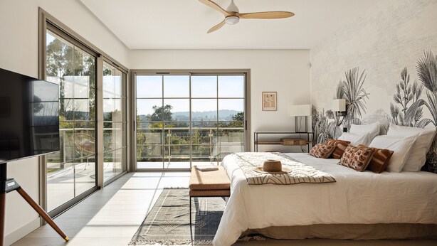 A bedroom with a large bed, a ceiling fan, a TV, and a view of the outdoors through large windows. - Luxury single-storey Villa on French Riviera , View & heated swimming pool (ST PAUL DE VENCE)