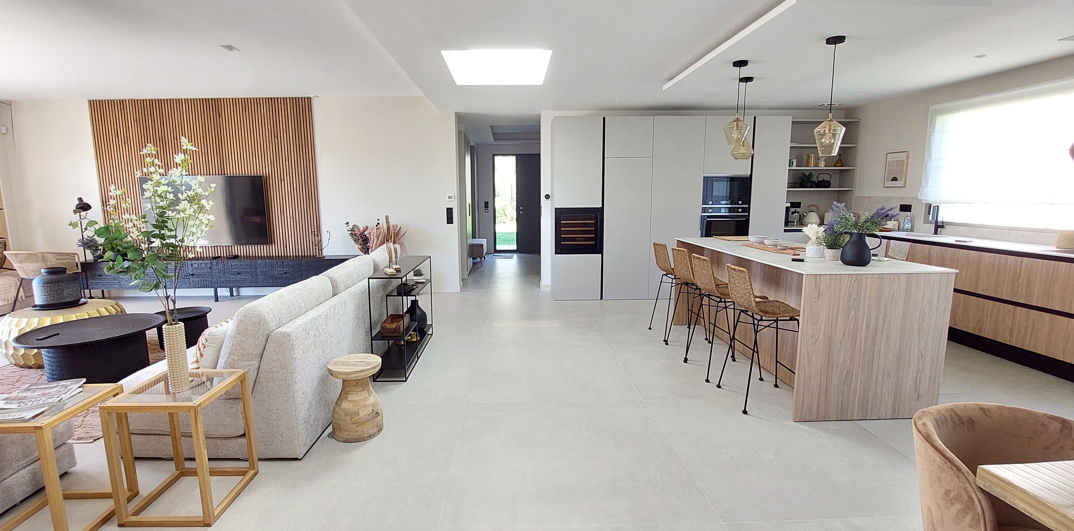 Eine moderne Küche mit Kochinsel, Barhocker und einem Essbereich mit Sofa und Couchtisch.